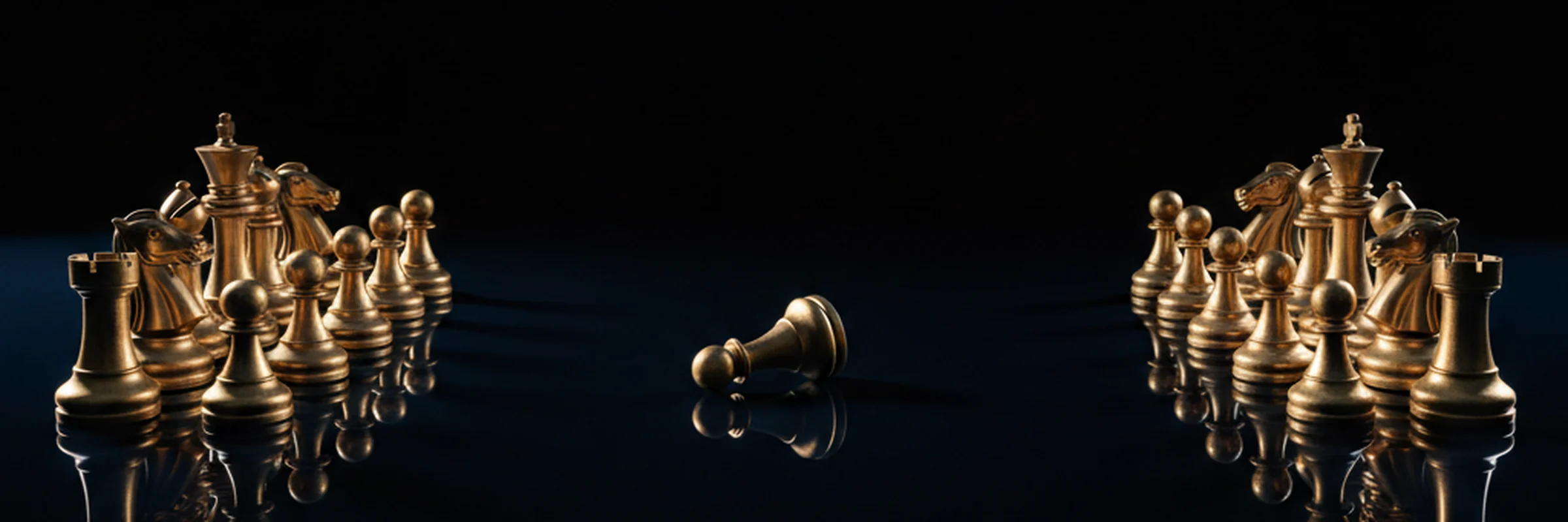 Gold chess pieces in two separated clusters with one piece toppled between them