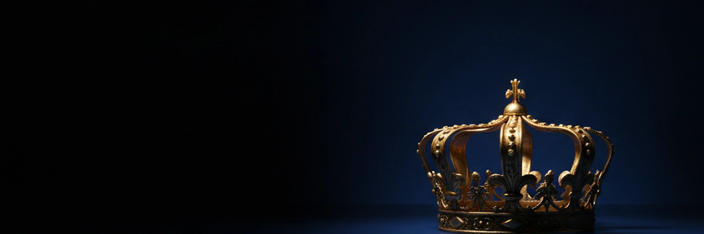 An ornate gold crown lit against deep royal-blue darkness