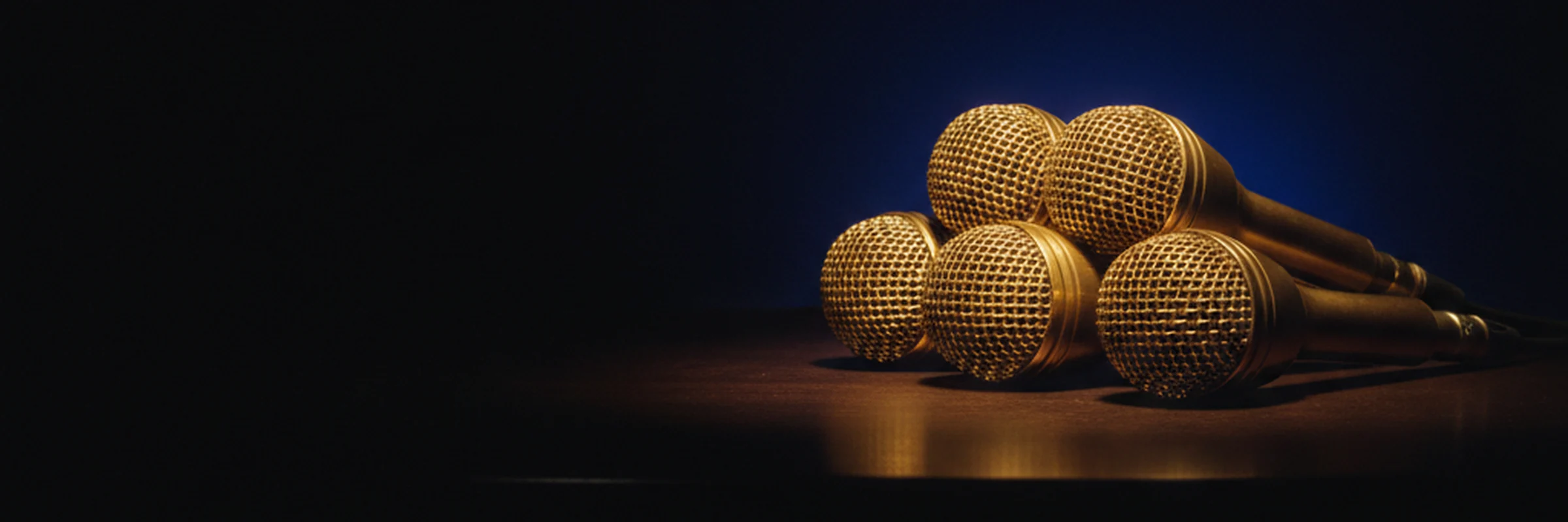 A single gold broadcast microphone emerging from darkness
