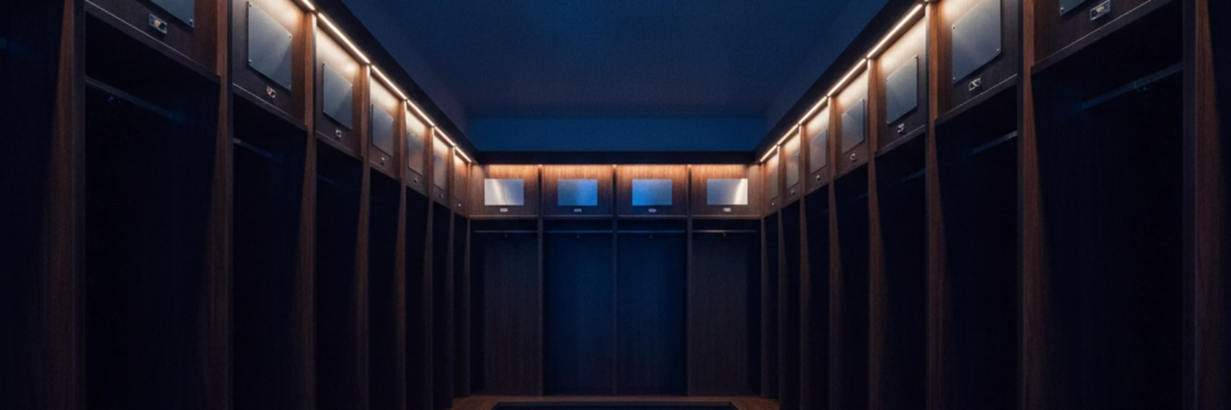 A deserted dressing room lit in gold and deep blue, lockers empty