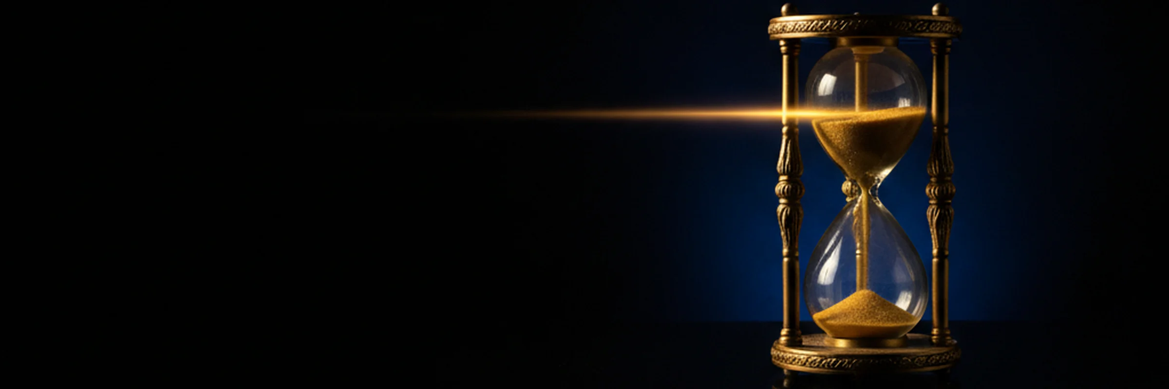An antique gold hourglass with falling sand, lit against deep royal-blue darkness